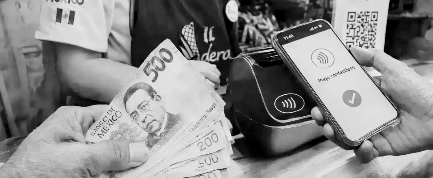 Billetes y monedas de peso mexicano junto a una terminal de pago con tarjeta sobre un mostrador