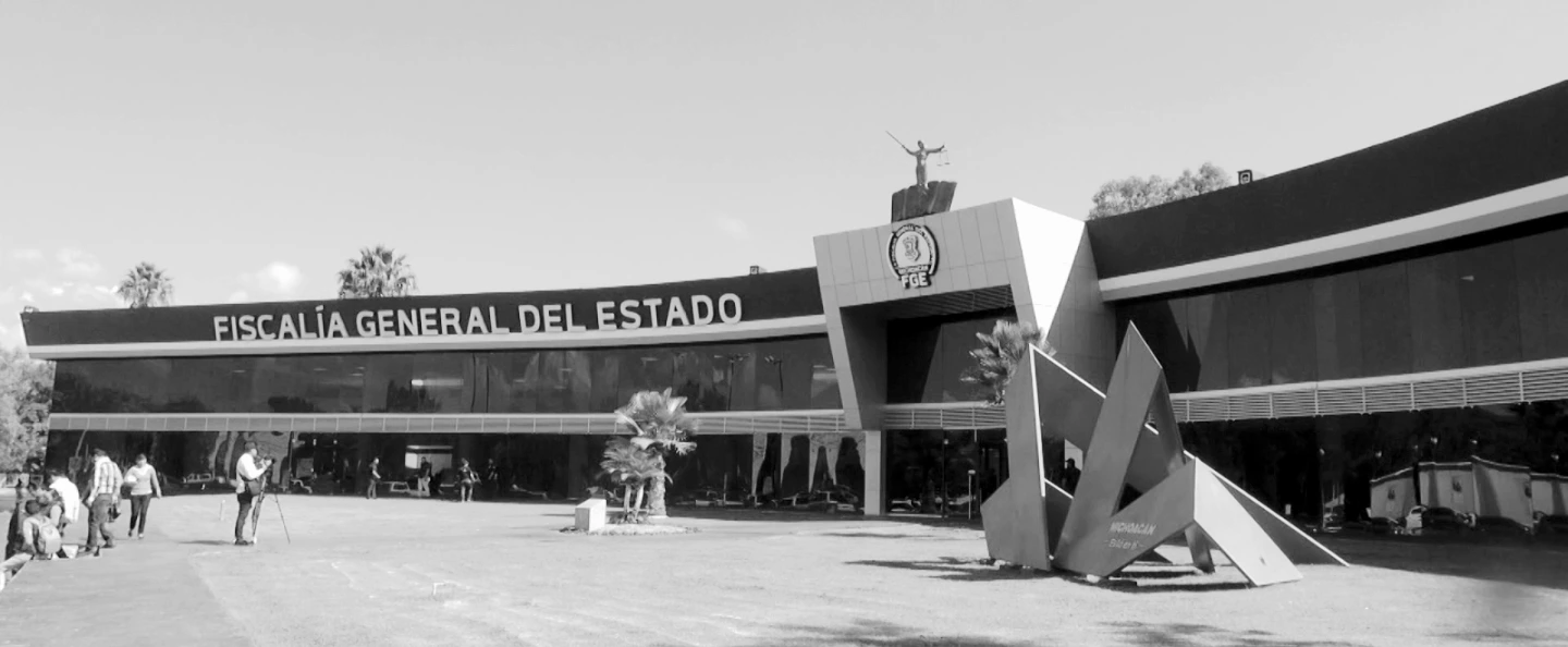 Fachada de la sede de la Fiscalía General del Estado de Michoacán con vehículos oficiales estacionados al frente