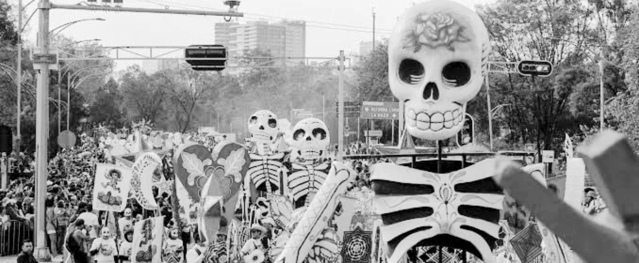 Carro alegórico con figuras de catrinas y flores de cempasúchil avanza por una avenida ante el público