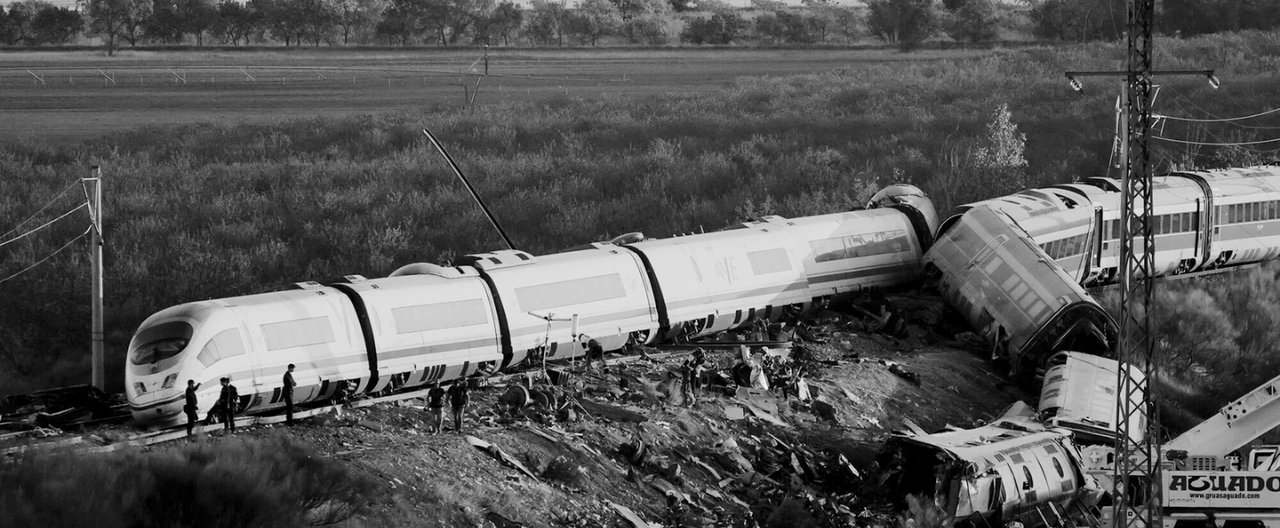 Vagones de tren descarrilados junto a la vía, con equipos de emergencia trabajando en la zona