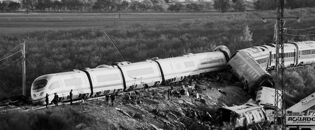 Vagones de tren descarrilados junto a la vía, con equipos de emergencia trabajando en la zona